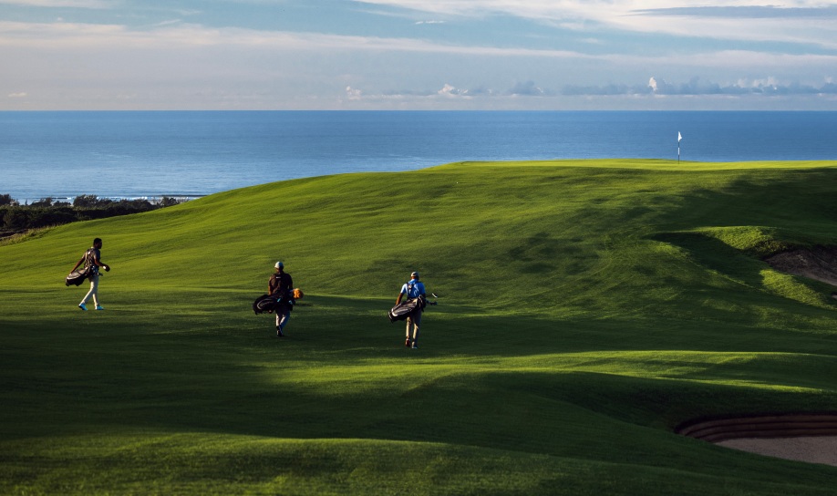Golfers walking on La Réserve Golf Links course with sea view