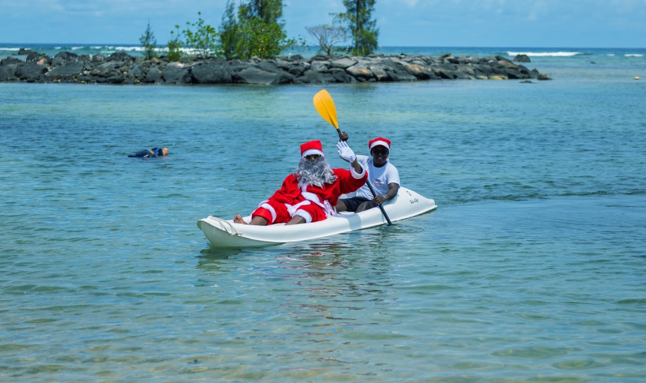 Santa Claus arriving in Mauritius on a paddleboard