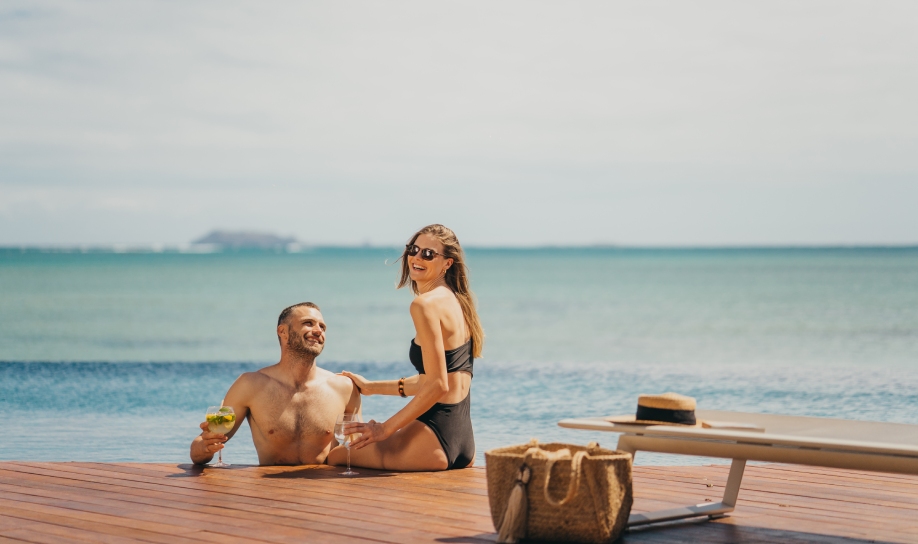 Couple se relaxant au bord de la piscine en sirotant un cocktail au Veranda Resort à l’île Maurice