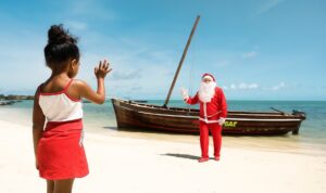 Père Noël arrivant par bateau sur une plage